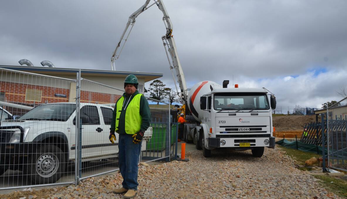 BUILDING CARE: Site supervisor Paul Murray stands in front of a concrete mixer truck pouring mix onto the extension site. 