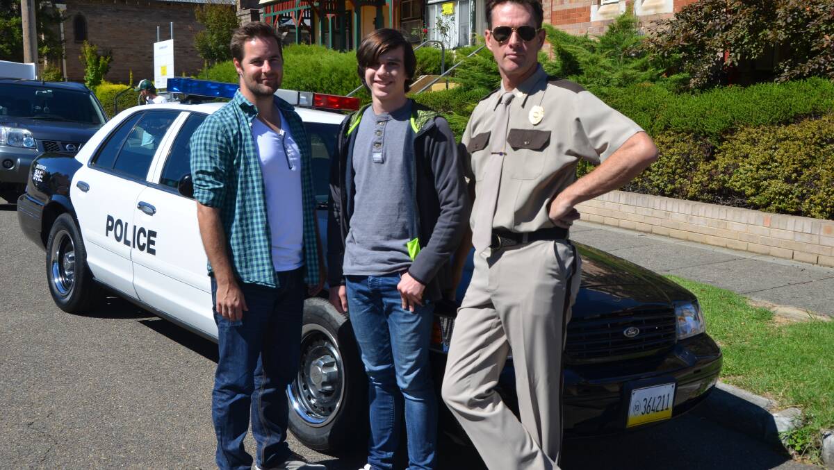 ROY STREET: Producer-director Matt Drummond, left, with actors Scott Irwin and Harrison Saunders and a genuine black and white Ford Crown Victoria. 