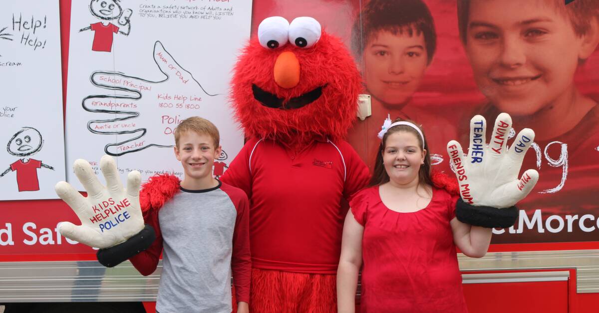 IN FRONT OF BIG RED TOUR BUS: Lithgow Public School captains Sam Doran and Lily Hazell with Elmo. Photo Troy Walsh.