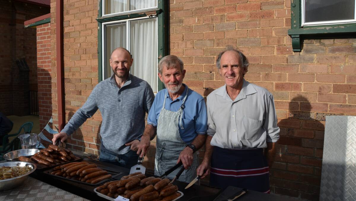 Reverend Mark Smith, Peter Avery and Garry Roberts behind the barbeque. Photo: HOSEA LUY