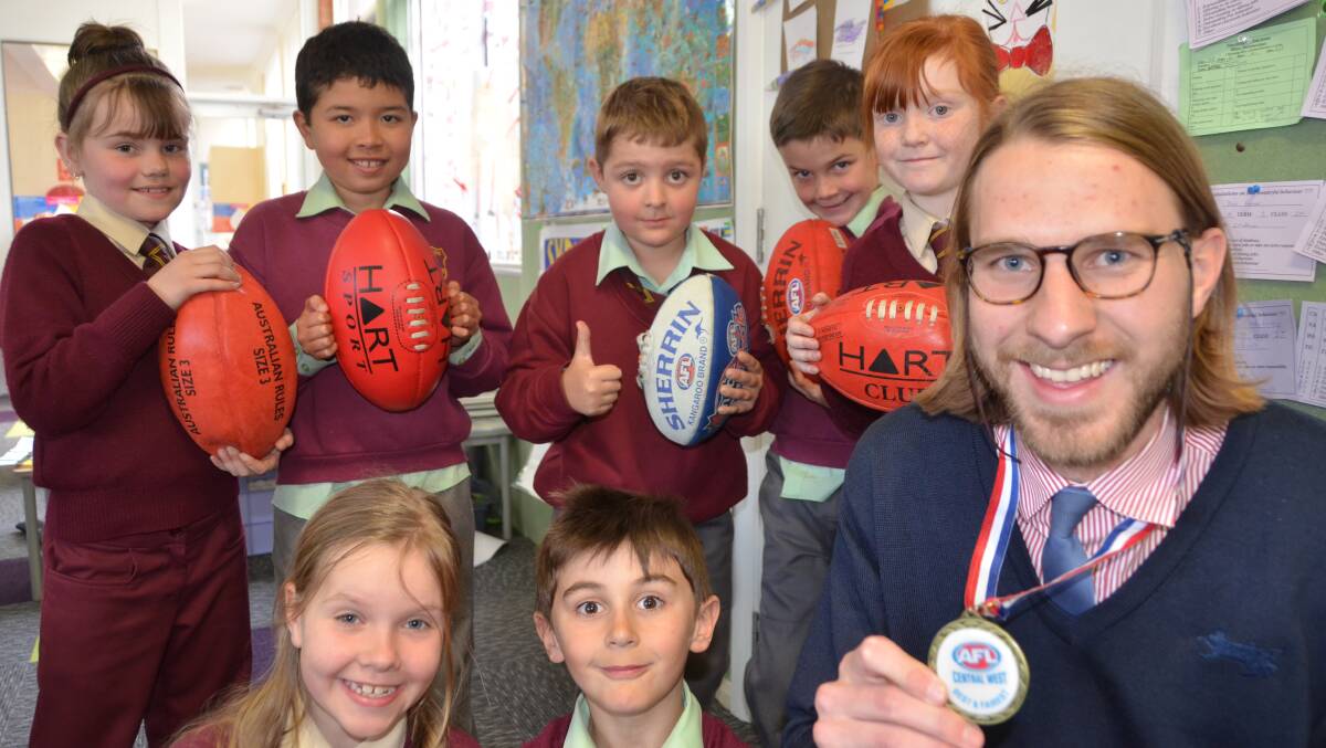 BEST AND FAIREST: St Patrick's School teacher Sebastian Matheson displaying his Central West AFL Best and fairest medal in the presence of several of his students. Picture: HOSEA LUY