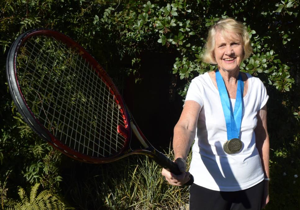 TRIPLE CROWN: Lithgow's June Kelly with her three gold medals from the World Masters Games and trusty tennis racquet. Picture: HOSEA LUY