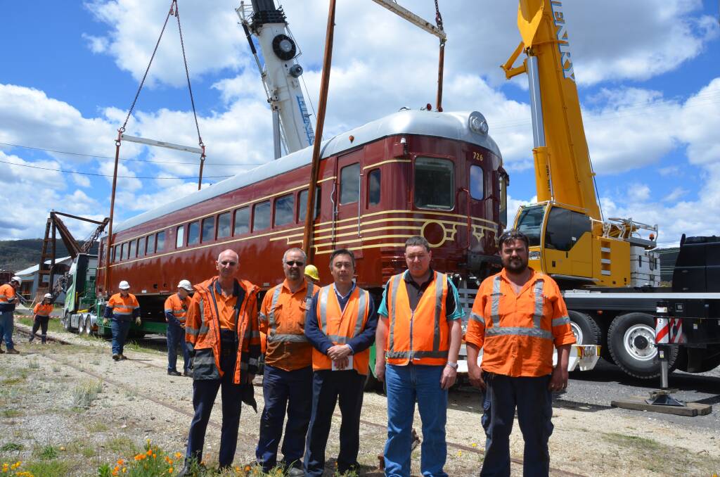 STRAPPED IN: Cranes lift the train into place at Eskbank Station. Pictured are Byron Bay Railroad's Robert Jarvis, Lithgow Railway Workshop's Nathan Carter, Tim Elderton and Anthony Rappard (right side) with Lachland Valley Railway driver Jason McIntyre. Picture: KIRSTY HORTON.