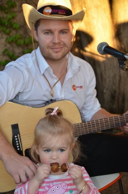 DIVIDED INTERESTS: Accomplished guitarist Aaron Staines kept the guests entertained with some light music but two-year-old daughter Indiana was more interested in what was on offer in the food line. 	lm101314LA0938