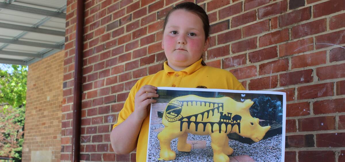 DEARLY MISSED: Zig Zag School student Chloe Murray holding a photo of "Ziggle Zaggle", the school's rhino statue that was stolen this week. PHOTO: Jacob Gillard. lm102716zig
