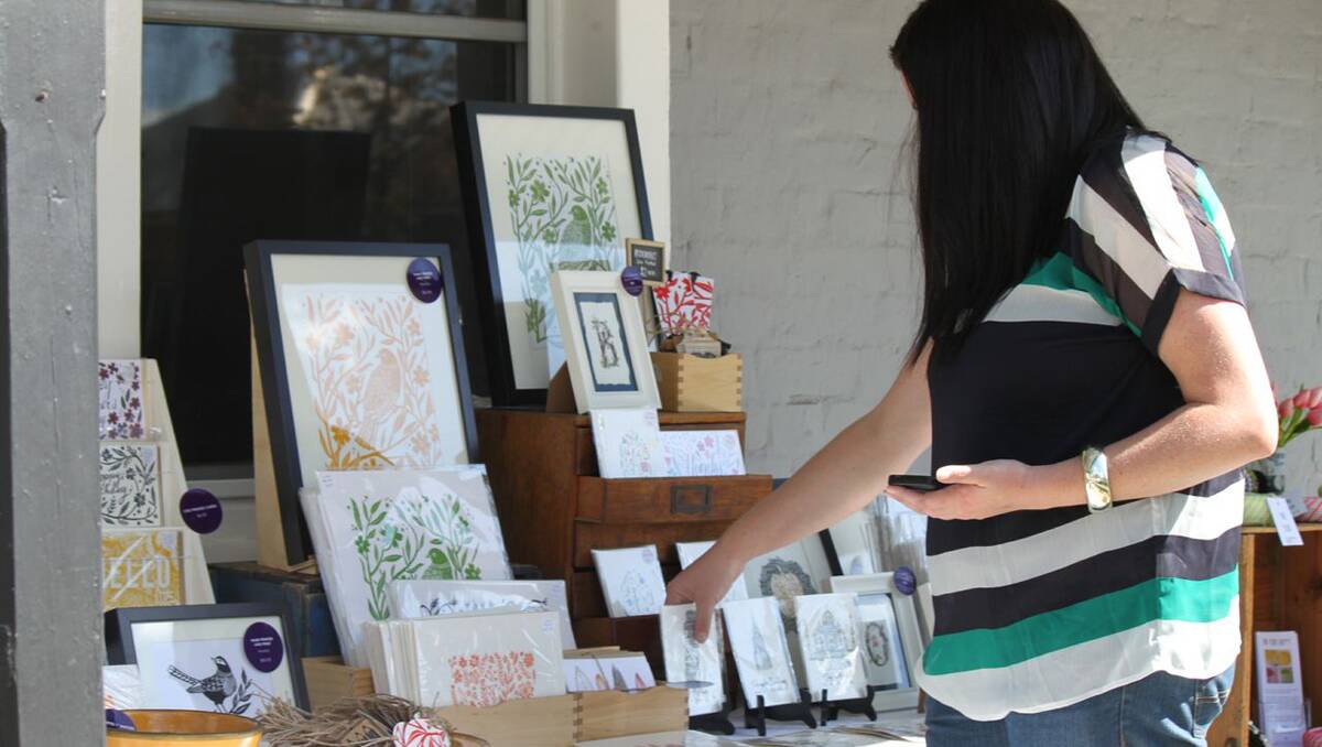 A visitor browses Amelia Herberston’s hand printed works at the Orange Verandah Markets. Photo: Sarah Powell