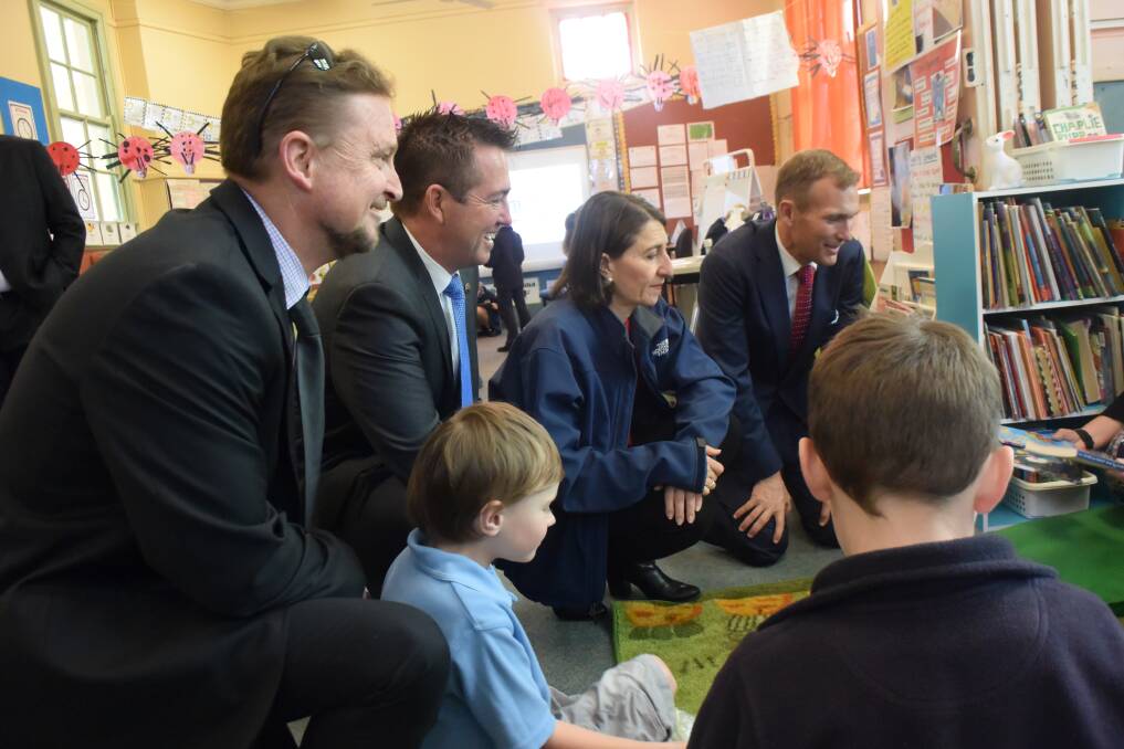 Principal Mark Davies, MP Paul Toole and Premier Gladys Berejiklian watch as education minister Rob Stokes gives books to the students. 