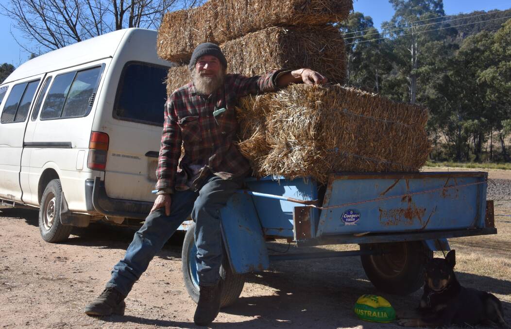 BALE OUT: Matthew Pilarcik with the converted bus he will be driving to Albury stacked with hay. Picture: PHOEBE MOLONEY
