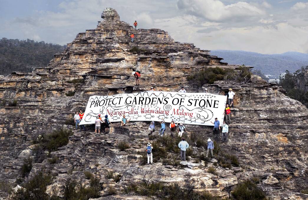 IN ROCK: Environmental campaigners spread banner on rock pagoda in the Gardens of Stone. Picture: HENRY GOLD.