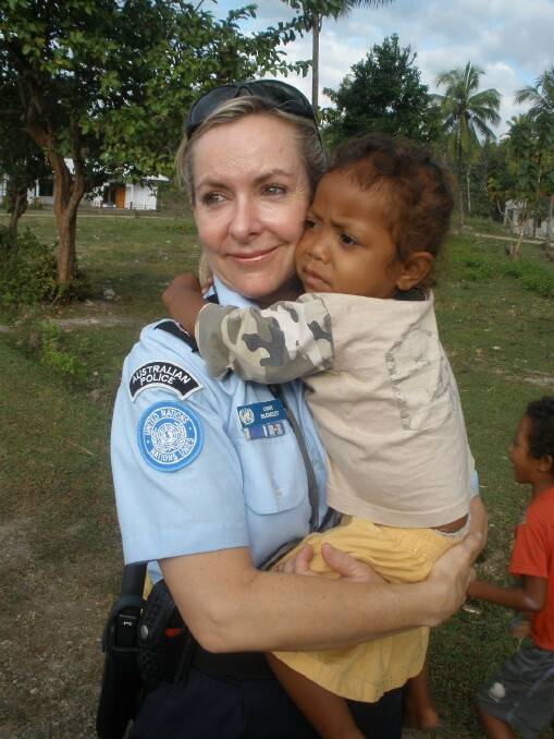 Personal aid program: Libby Bleakley with a young child in East Timor. The former police officer has set up a community centre in Dili.