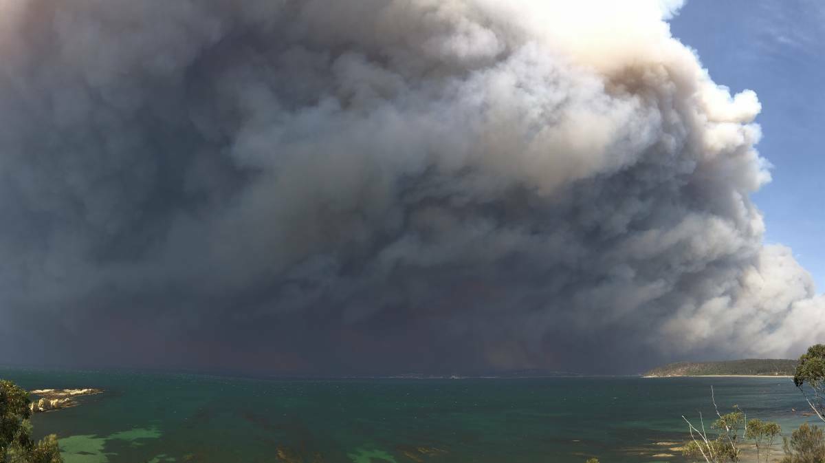 Photo taken from Longbeach clifftop, looking back towards the bay on morning of New Year's Eve, 2019. Flaming debris is falling from the smoke cloud. Picture: David Shearer
