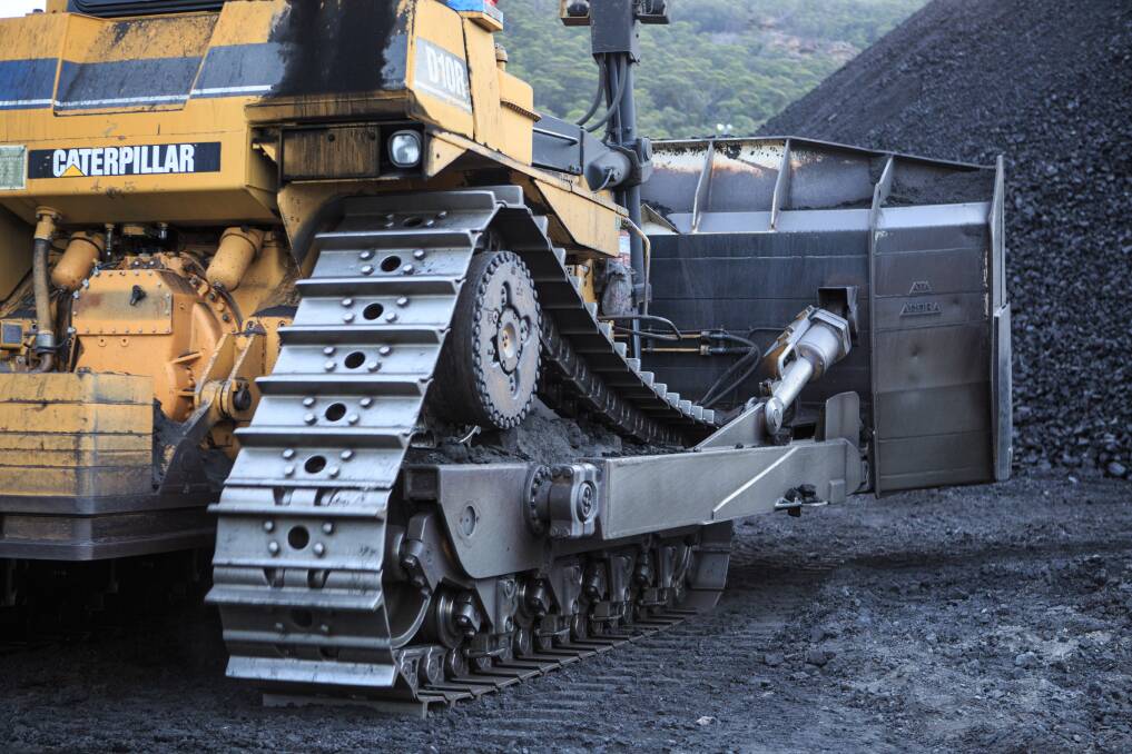 Mountains of coal: A huge dozer tidies up a coal stockpile at Springvale mine.
