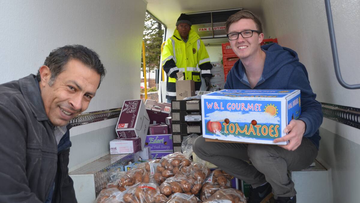 St Paul's Anglican Church members Eric Rizk and Samuel Ogg unpacking the fresh food van on Friday alongside Robin from Anglicare. Picture: HOSEA LUY