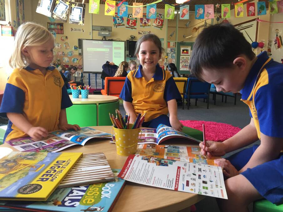 EXCITED TO SELECT BOOKS: Kindergarten students Alyssa Tully, Lily James and Cameron McAndrew. Picture: KIRSTY HORTON.
