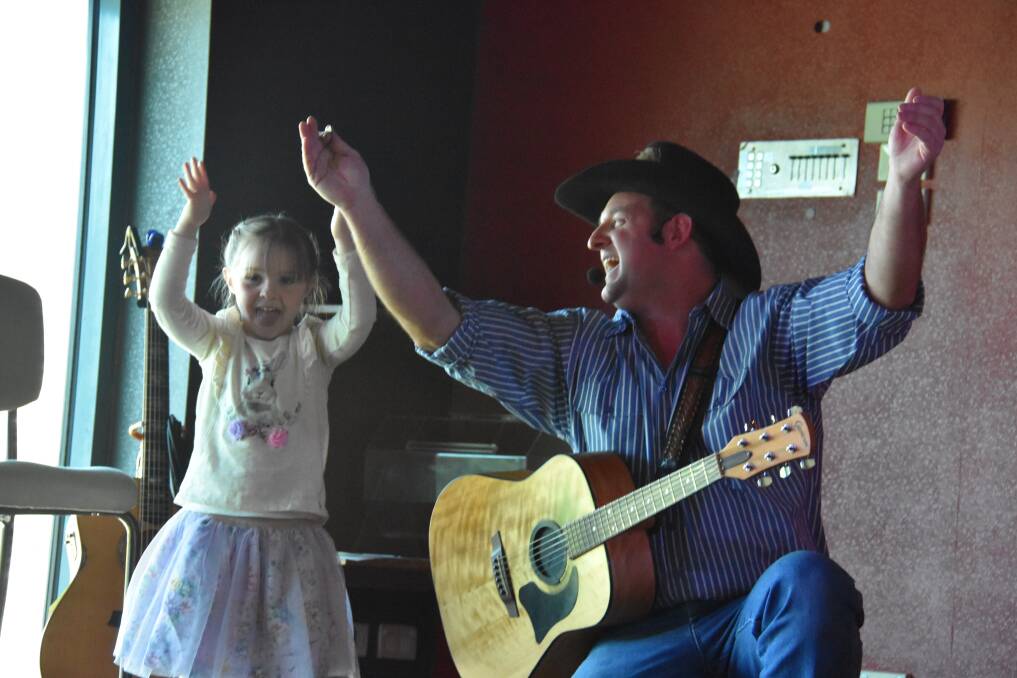 HANDS TOGETHER NOW: Performer Dean Taylor is joined on stage at the Workies by his daughter Amelia. Picture: KIRSTY HORTON. 