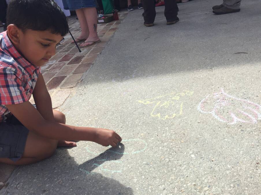 MESSAGES: Children took the opportunity to draw doves and other peace designs on the cement. 
