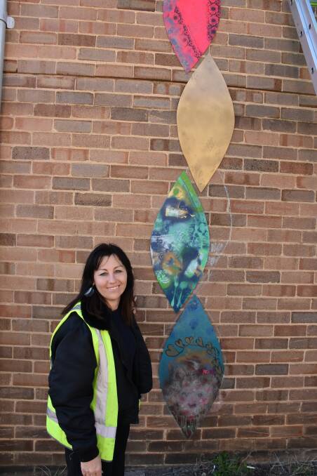 SEASONS: Natalie Topaz with the start of her artwork being installed on the exterior library wall. Picture: CIARA BASTOW. 
