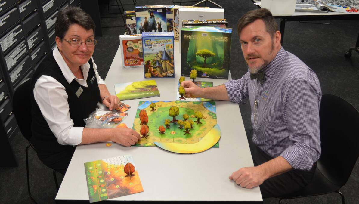 GAME DAY: Julie Sykes and Sean Brady show off some of Orange City Library's huge selection of board games to play these school holidays. Photo: ALEX CROWE 0210acgames2