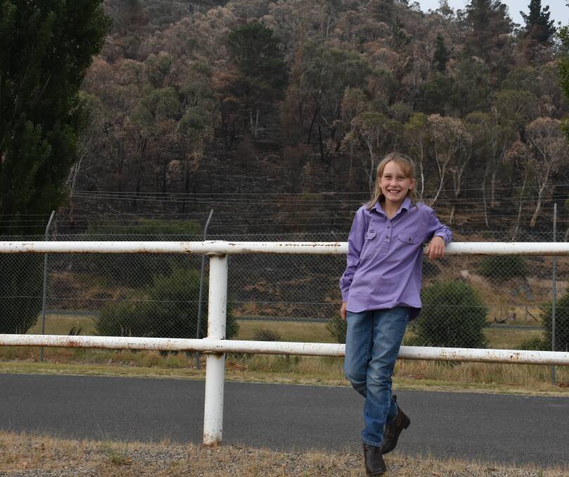 THE SHOW MUST GO ON: Junior show member Olivia Wiggins stands in front of the burnt mountain behind the showground but she won't let the fire get her down. Picture: ALANNA TOMAZIN.