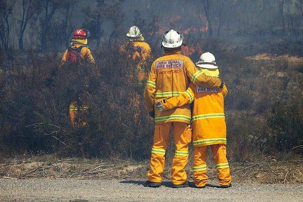 SW RFS Crews continue to fight the State Mine fire on the Darling Causeway near Bell as they back burn onto the fire front. RFS crew members give each other a hug as the hard work continues. Photo: Wolter Peeters